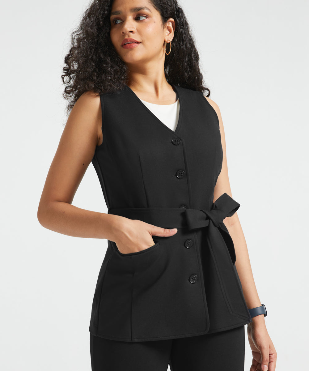 Woman wearing black button-front ponte vest with V-neckline, tie waist and hand in front pocket