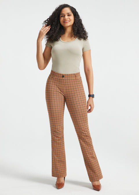 A woman modeling brown and beige checkered flared trousers, standing against a light gray studio background.
