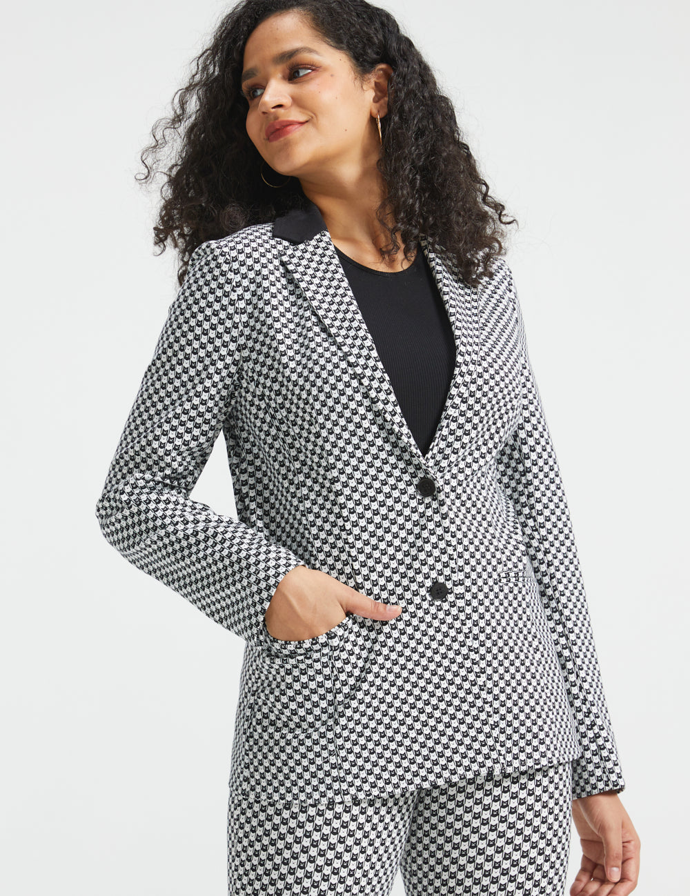 Woman wearing the black and ivory cat print Classic Blazer buttoned with one hand in the functional front pocket